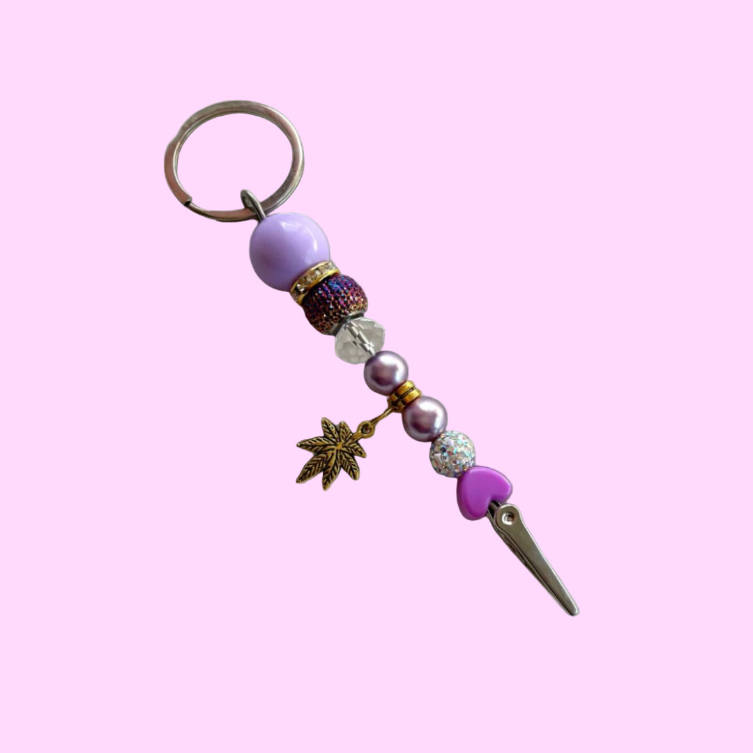 purple and gold beaded roach clip with rhinestones and a gold cannabis leaf charm, handmade by Trap Mami LA.