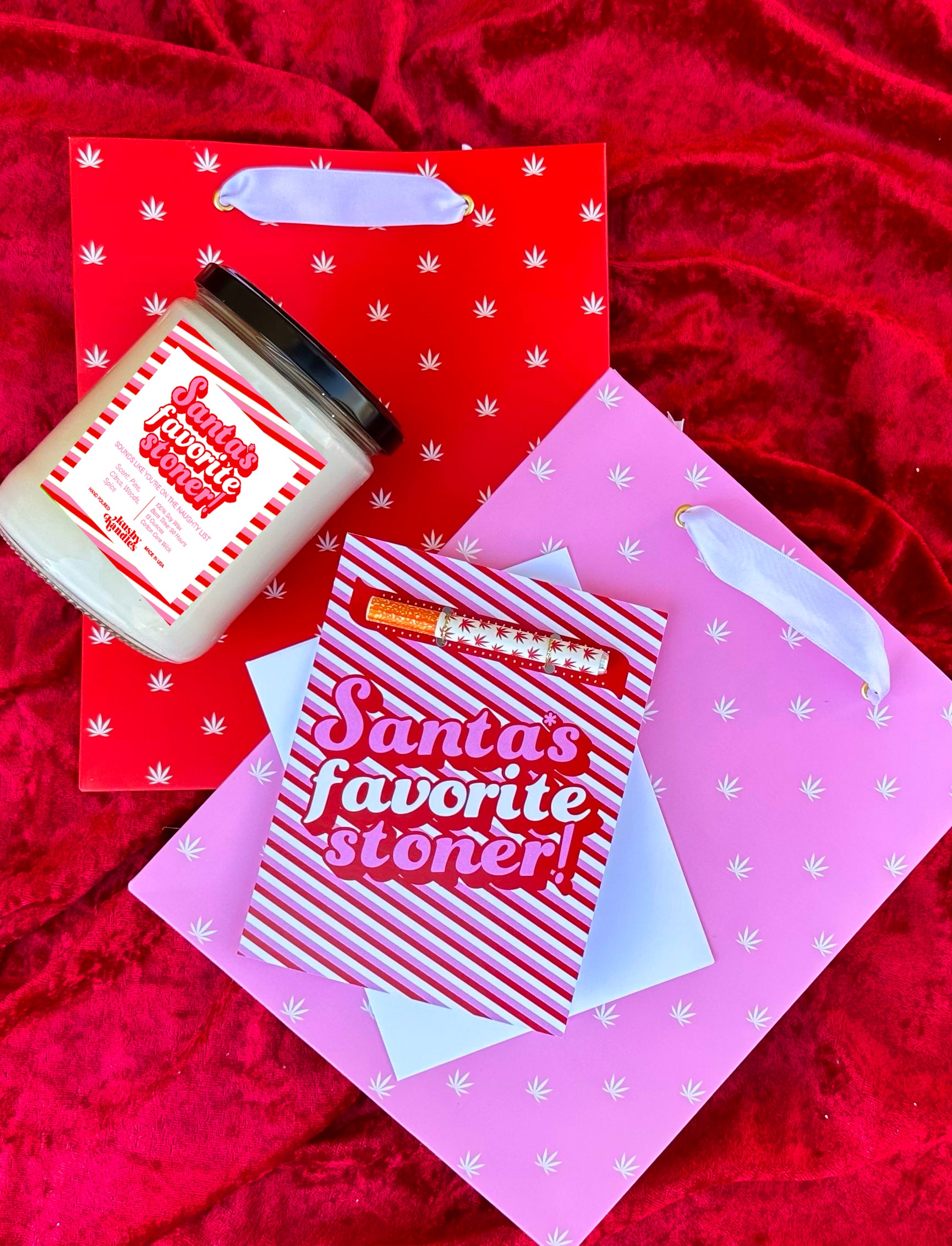 santas favprite stoner candle and matching one hitter greeting card with a pink and red gift bag on a red velvet background