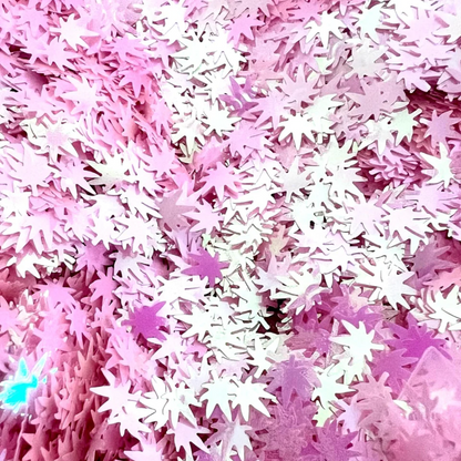 Close-up of pink cannabis leaf-shaped confetti scattered densely.
