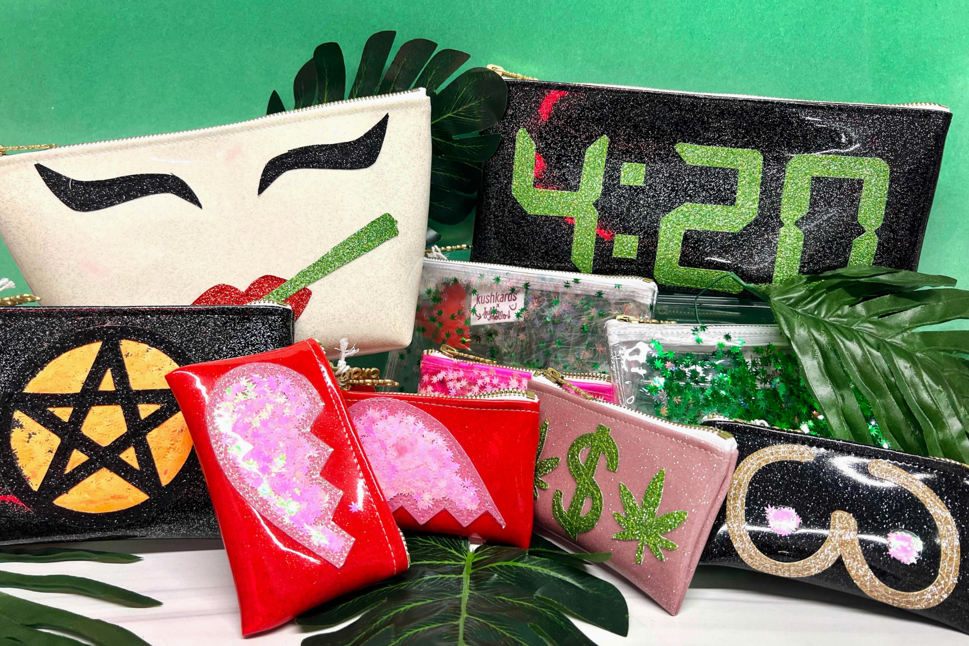 A collection of vibrant, themed clutch bags displayed against a green backdrop with tropical leaves. Designs include a pair of red lips with a joint, a black bag with a sparkly pentagram, a digital clock reading 4:20, and others with broken heart, dollar sign with cannabis leaf, and sparkly glasses motifs. The bags feature a glittery, eye-catching aesthetic, suggesting a fun and bold fashion statement.