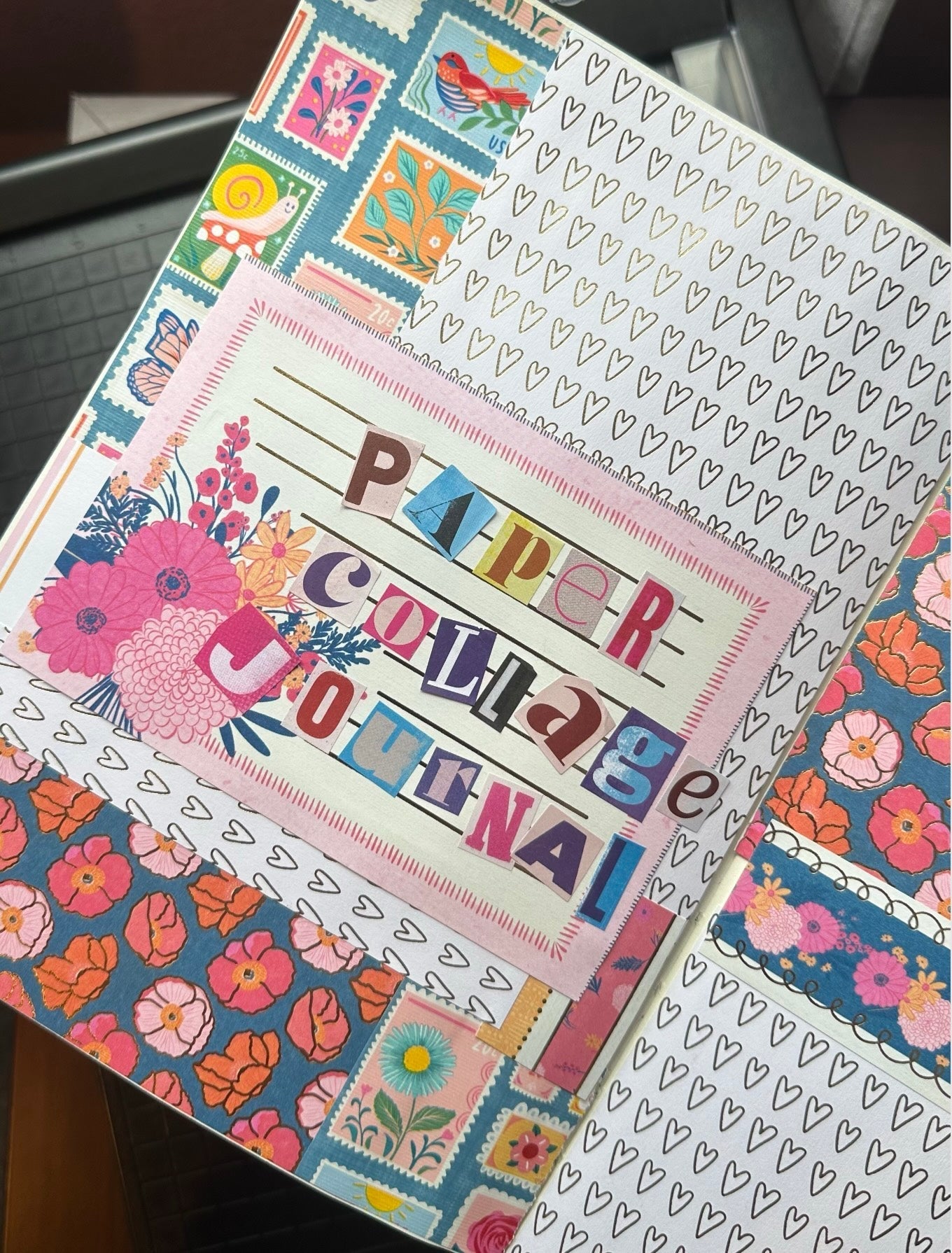 Open paper collage journal with 'Paper Collage Journal' title, stamp patterns, and floral designs