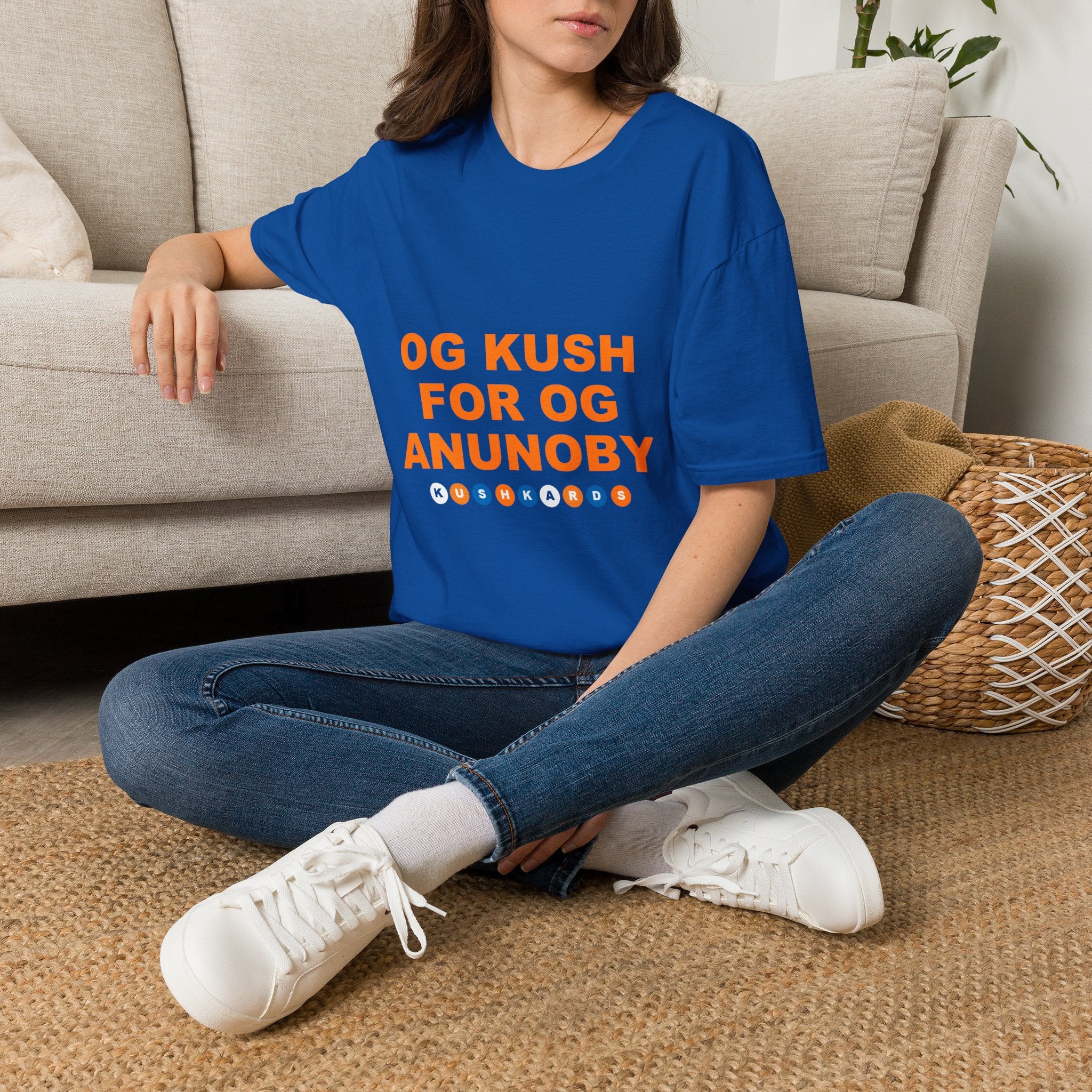 Person wearing a blue t-shirt with a graphic design sitting on the floor.