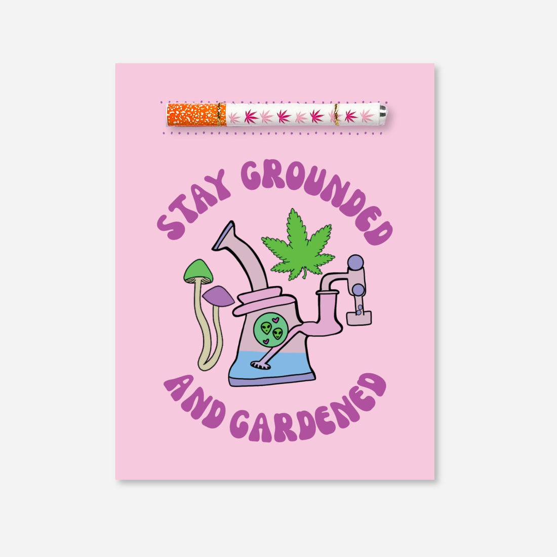 Pink cannabis-themed card with a one-hitter pipe included and artwork featuring mushrooms, a leaf, and alien in a bong. Text reads “Stay Grounded and Gardened.” Collaboration with A Psychedelic Mood.
