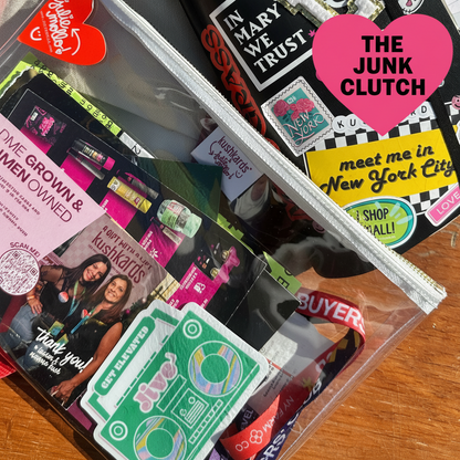 Clear Junk Clutch Filled on a table with red heart tag and branded label 