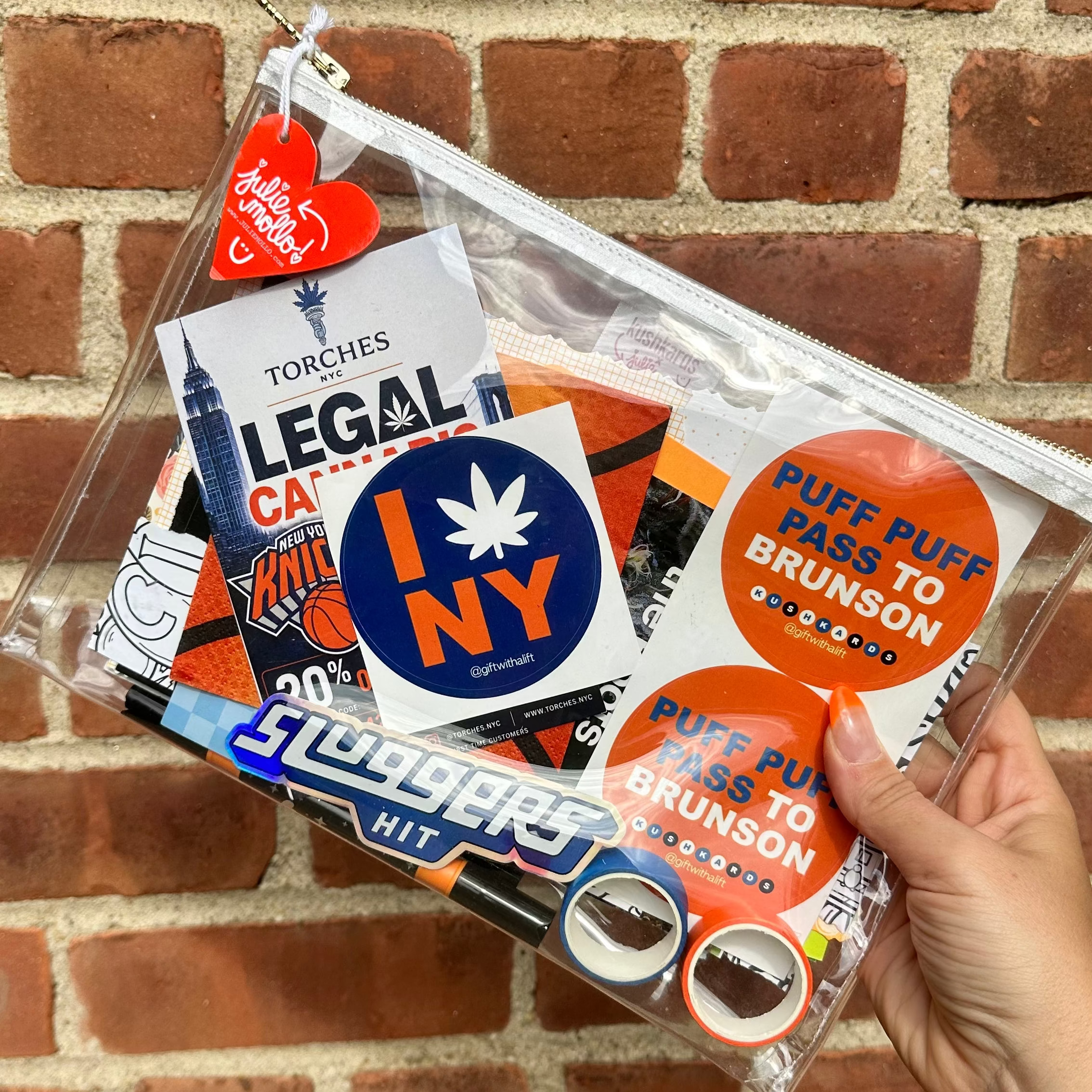Clear plastic bag with various stickers held against a brick wall