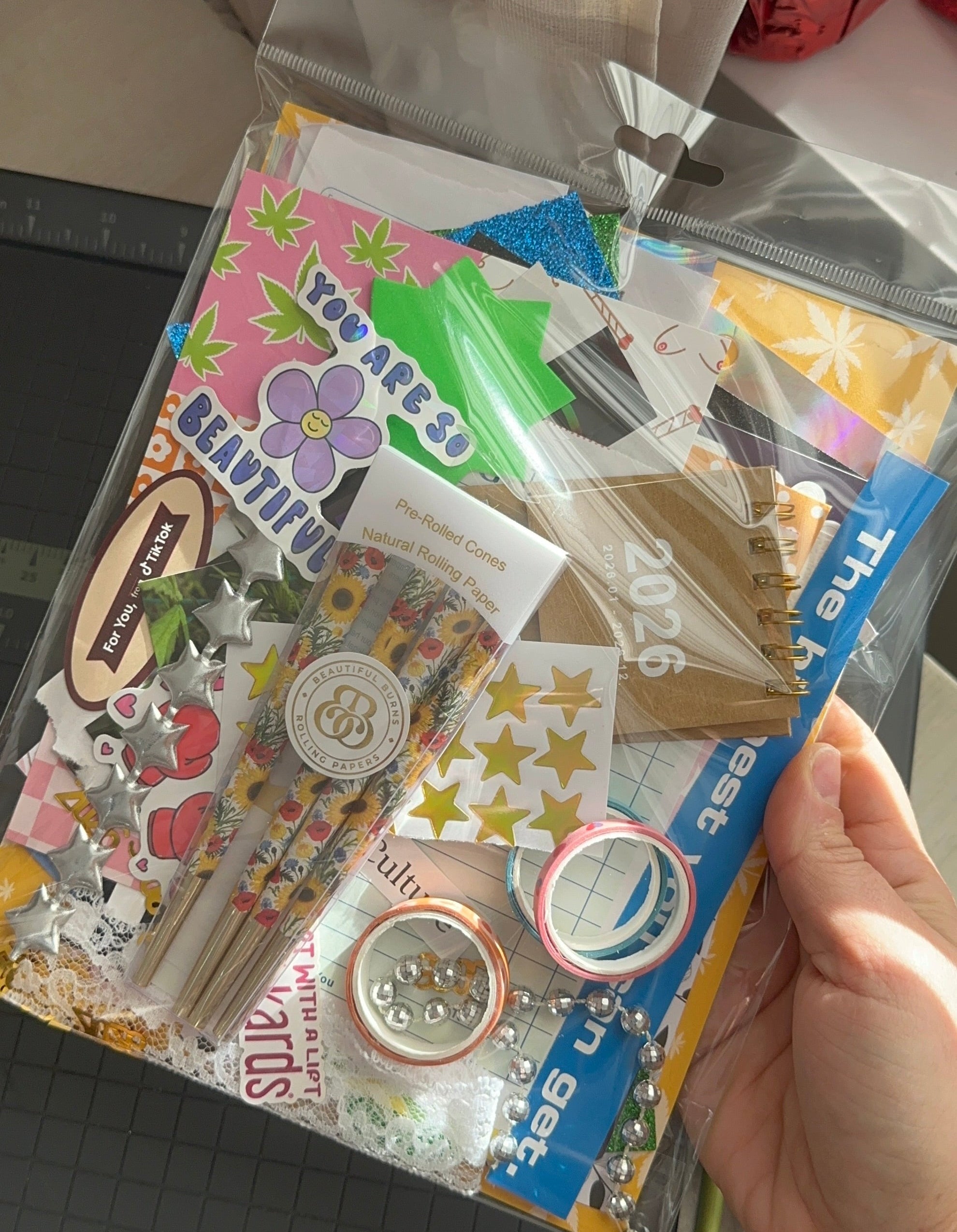 Hand holding a package of stationery items including stickers and washi tape.