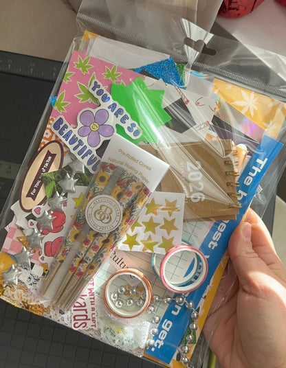 Hand holding a package of stationery items including stickers and washi tape.