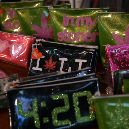 Assortment of customizable Kush Clutches with cannabis leaf designs on display.