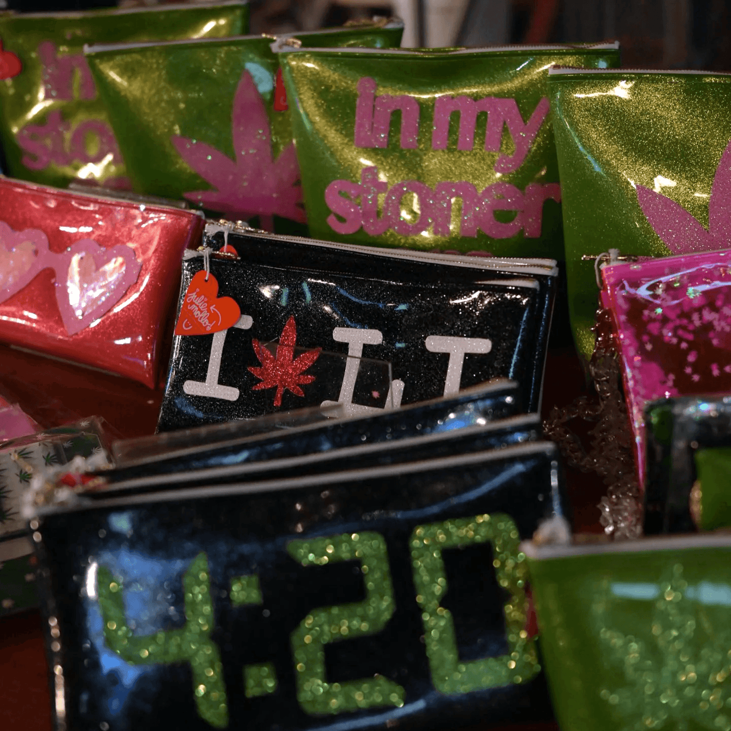 Assortment of customizable Kush Clutches with cannabis leaf designs on display.