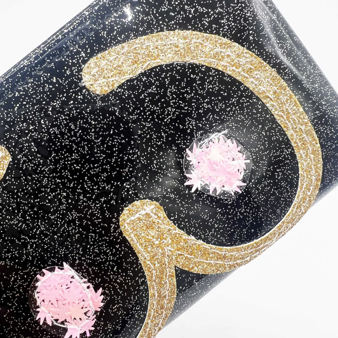Detailed view of black glitter vinyl clutch with gold outlines and pink cannabis leaf confetti.