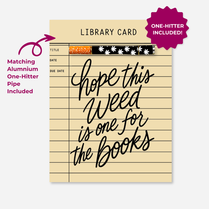 Hope This Weed Is One for the Books KushKards cannabis greeting card designed to resemble a vintage cream-colored library checkout card with black ruled lines, title, date, and due date fields. Large black handwritten lettering reads “Hope This Weed Is One for the Books.” A matching aluminum one-hitter pipe with an orange-speckled tip and black-and-white cannabis leaf pattern is attached horizontally near the top. A magenta arrow identifies the matching aluminum one-hitter, and a magenta badge reads “One-Hi