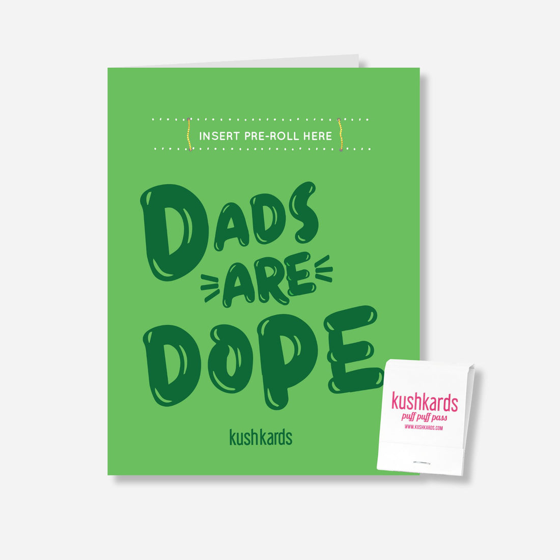 “Green greeting card with bold dark green text that reads ‘Dads Are Dope’. A blank slot is positioned above the text for inserting a pre-roll. A small KushKards-branded matchbook is shown next to the card. The card stands upright on a clean white background.”
