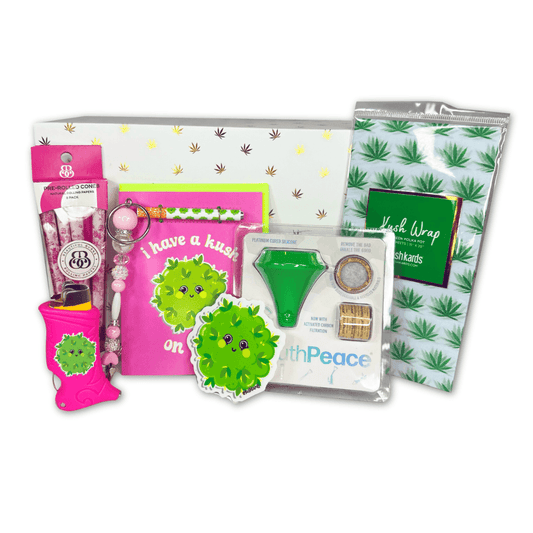 A refined 'Kush On You Valentine's Gift Box' with smoking accessories including a one-hitter card, mouthpiece, sticker, roach clip, rose-flavored pre-roll cones, all beautifully arranged in a themed white and gold box for your special someone.