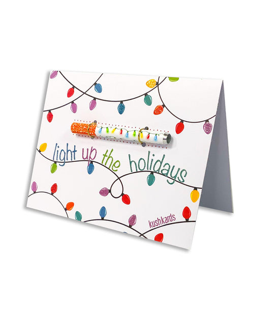 Elegant Christmas card with a white background, adorned with colorful Christmas lights and 'Light Up The Holidays' written in beautiful script.