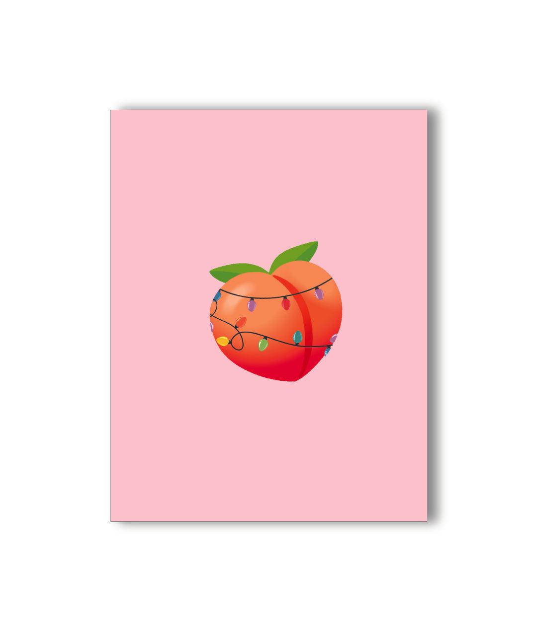 Cheeky and festive Christmas card with a pink background, featuring a peach emoji wrapped in holiday lights, perfect for spreading playful and fun holiday vibes.